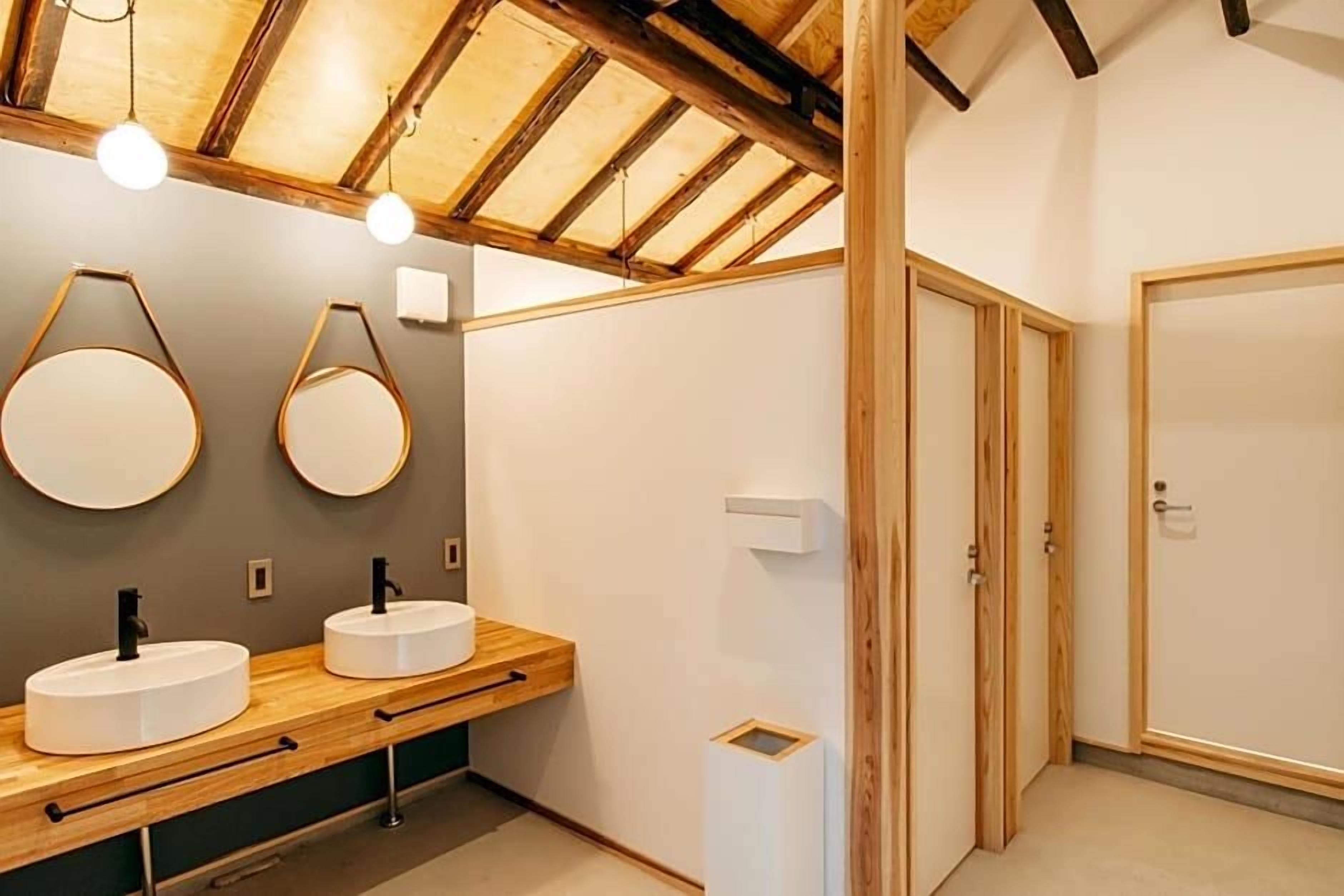 A modern bathroom with wooden beams, two round mirrors, and a wooden vanity with a sink.