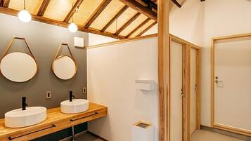 A modern bathroom with wooden beams, two round mirrors, and a wooden vanity with a sink.