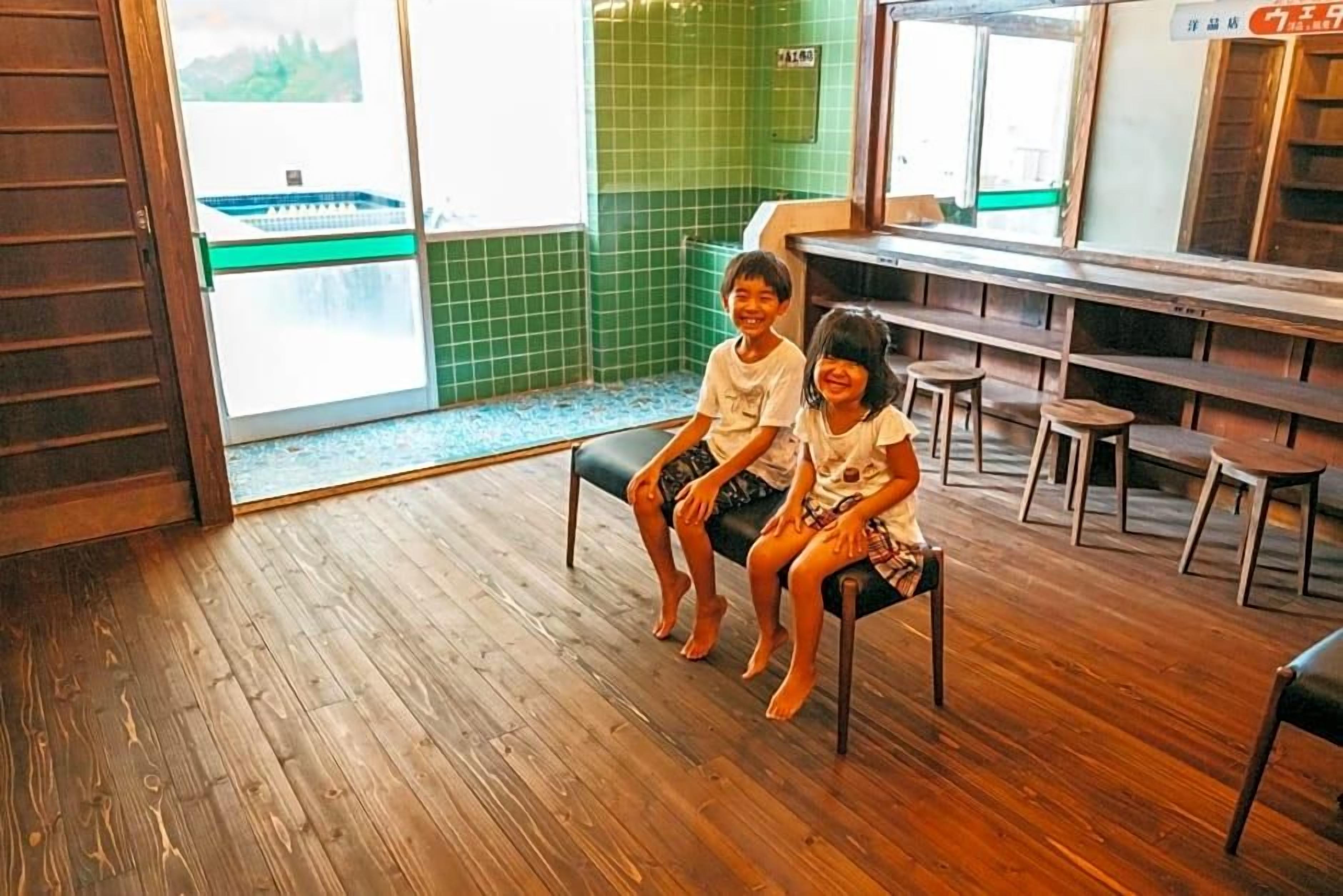 A wooden floor, a bench, and a green tiled wall.