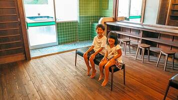 A wooden floor, a bench, and a green tiled wall.