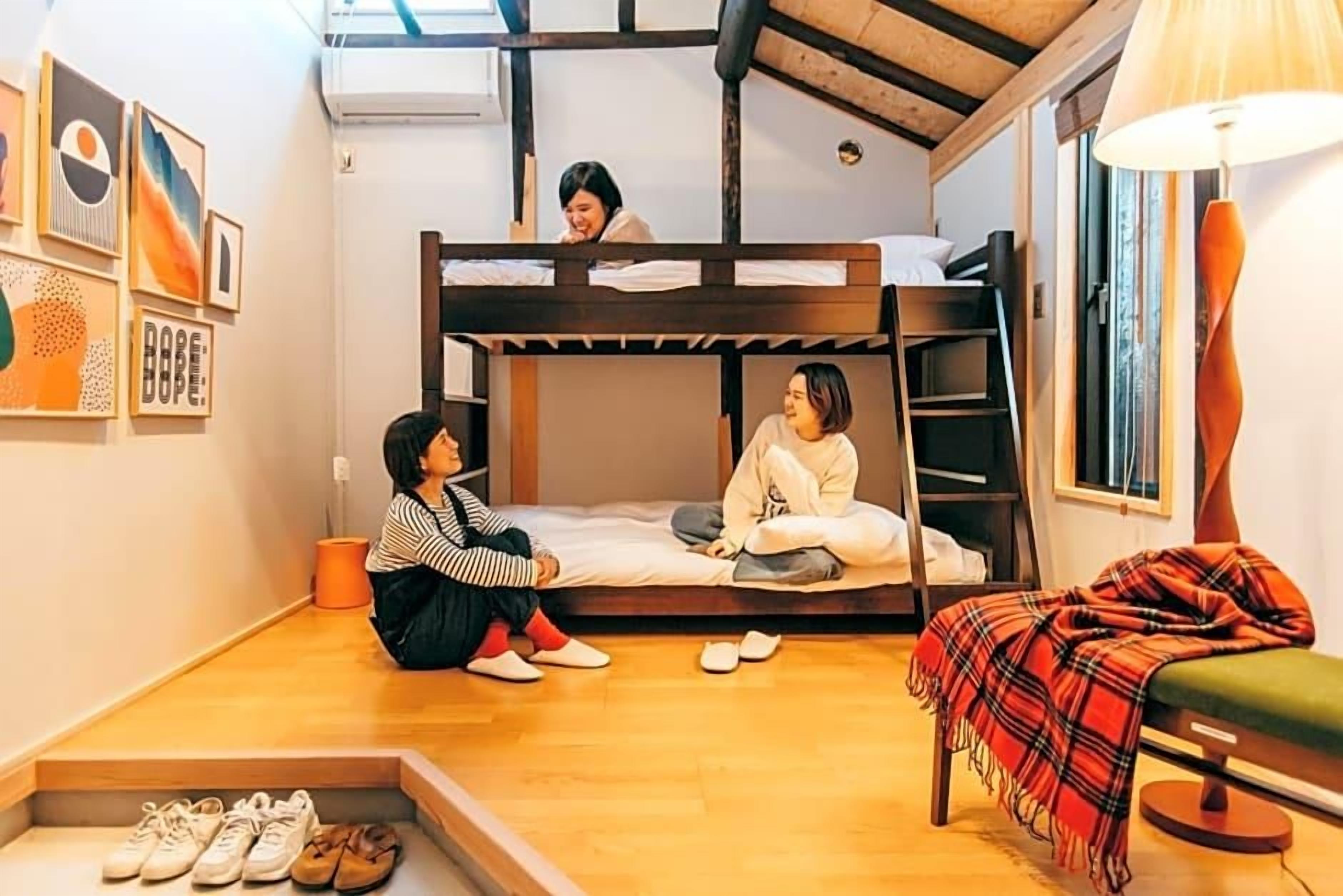 A room with a bunk bed, a desk, a chair, and a lamp.