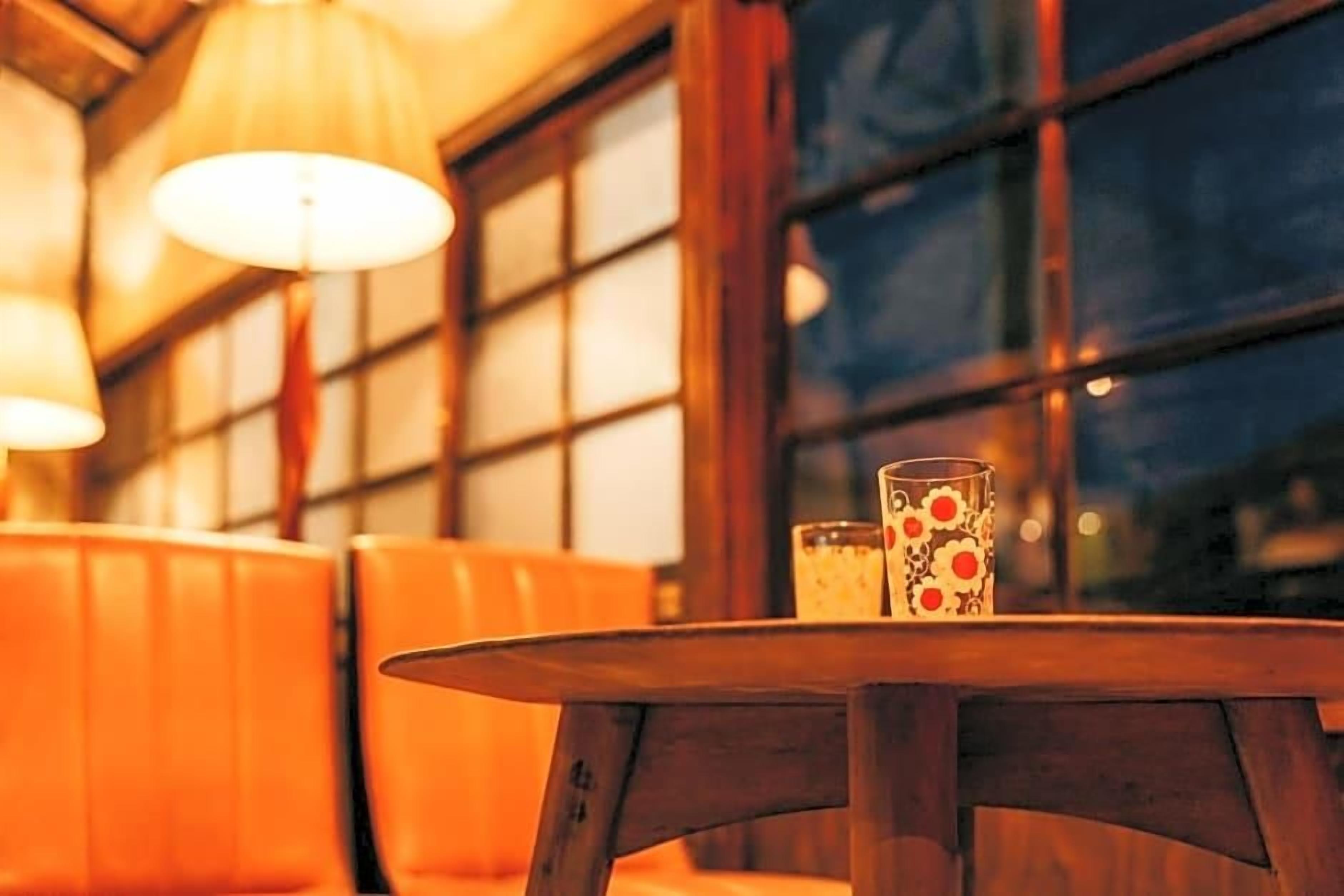 A round wooden table with a glass and a candle.