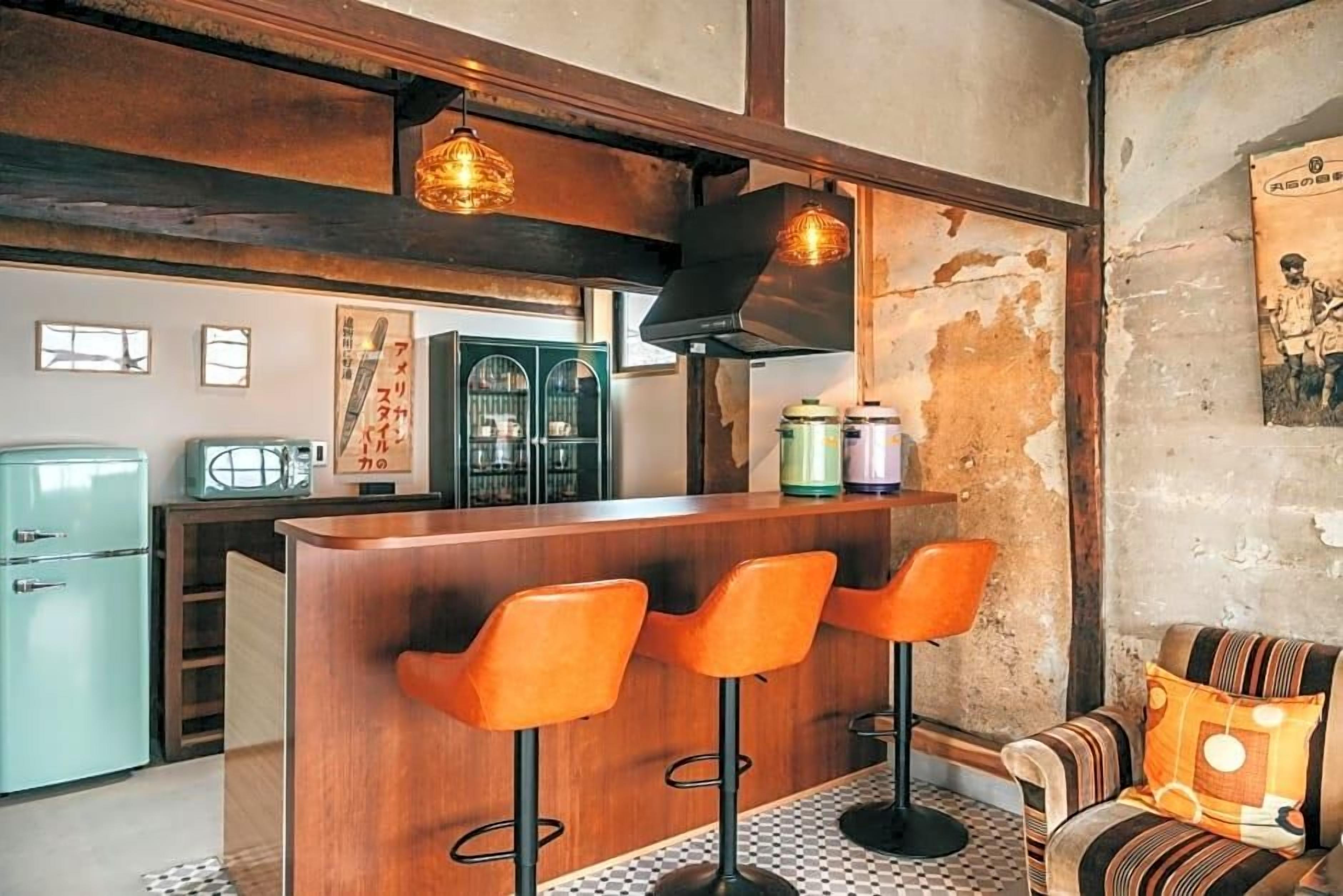 A bar area with wooden stools, a counter, and hanging pendant lights.