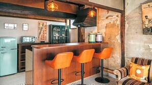 A bar area with wooden stools, a counter, and hanging pendant lights. - Yado Charinko (Gose)