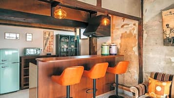A bar area with wooden stools, a counter, and hanging pendant lights.