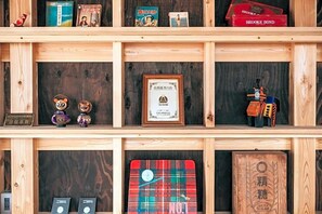 A wooden shelf with various items including books, figurines, and framed certificates. - Yado Charinko (Gose)