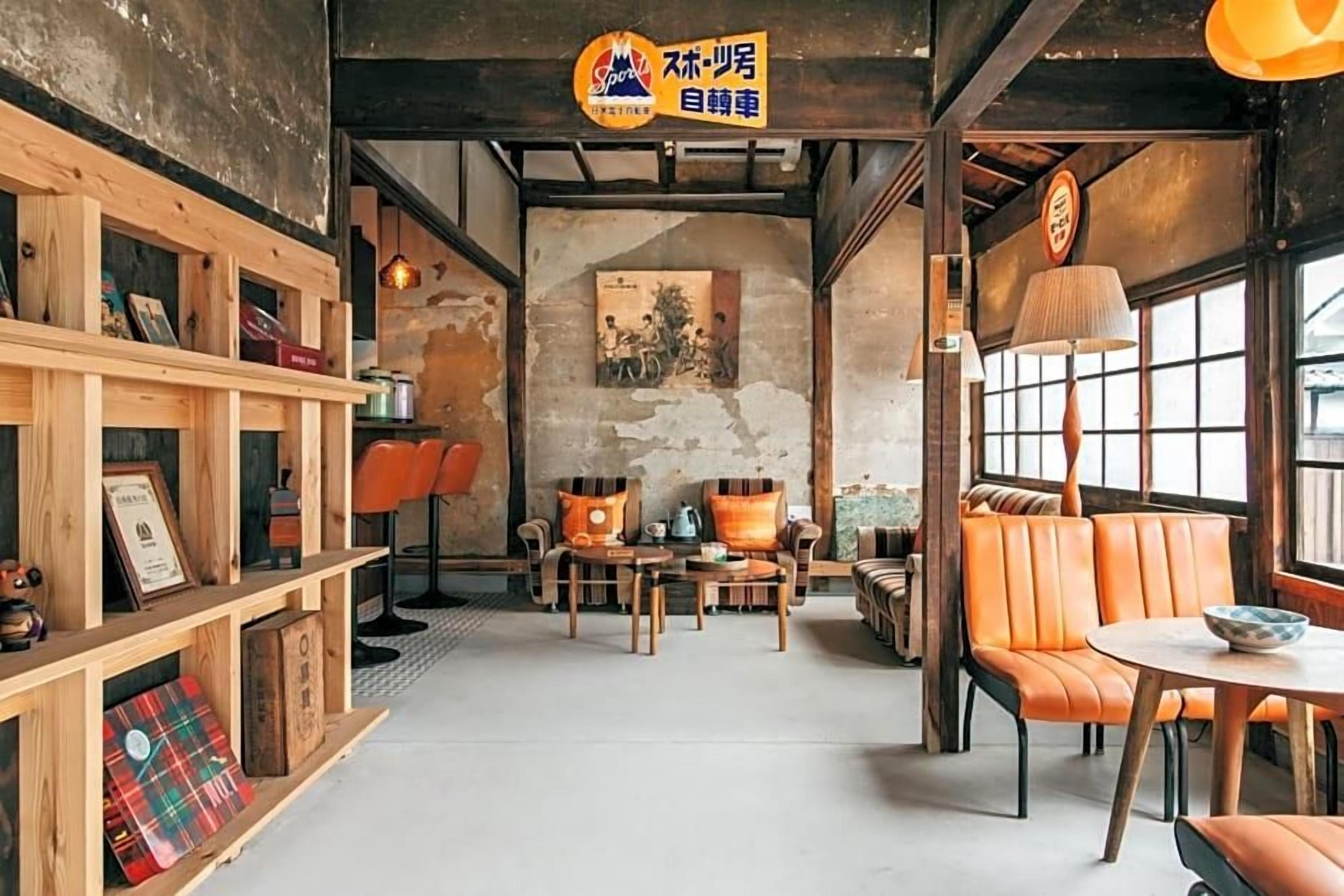 A cozy cafe interior with wooden shelves, orange leather seating, and a vintage poster on the wall.