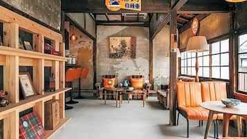 A cozy cafe interior with wooden shelves, orange leather seating, and a vintage poster on the wall.