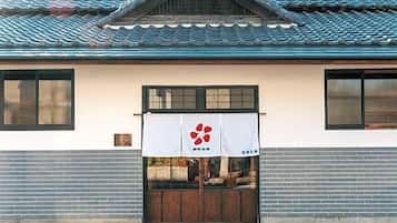 A traditional building with a tiled roof, a wooden door, and a white banner with a red logo.