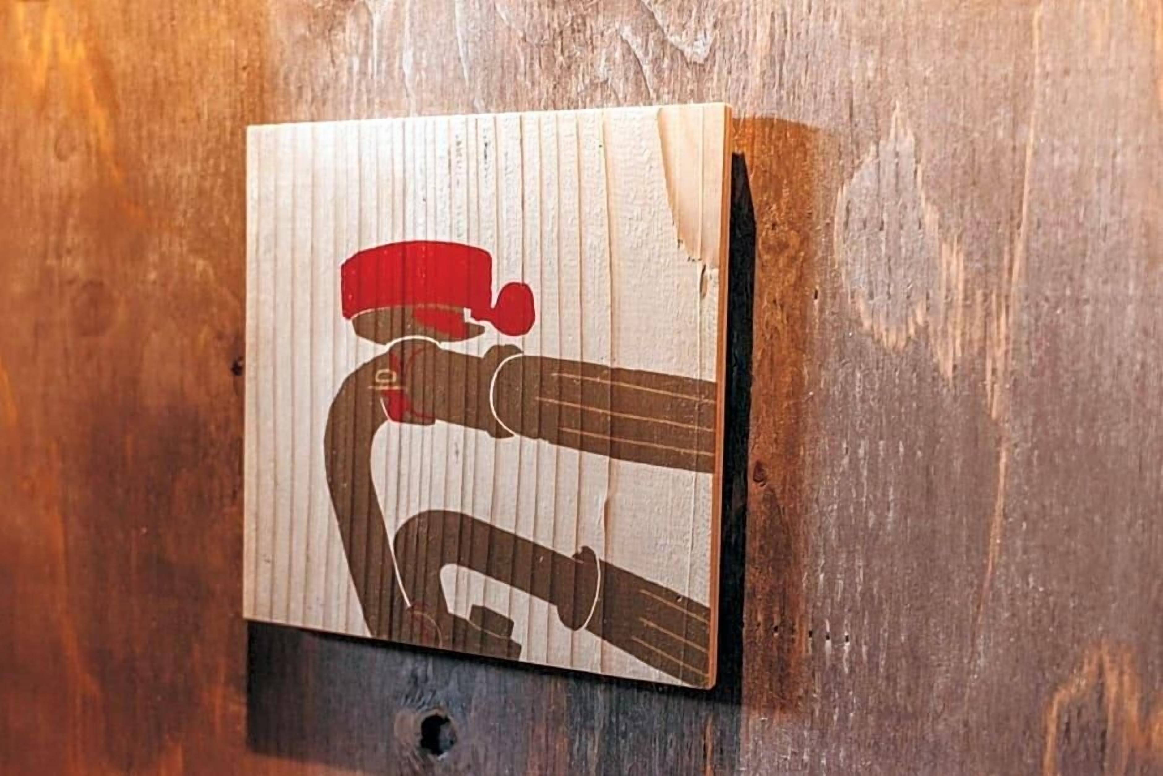 Une plaque en bois, avec un motif rouge et marron, qui pourrait indiquer le numéro d’un bâtiment ou d’une pièce.