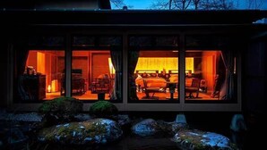 A modern building with large glass windows, a stone pathway, and a small pond with rocks. - Tokisumika (Komagane)