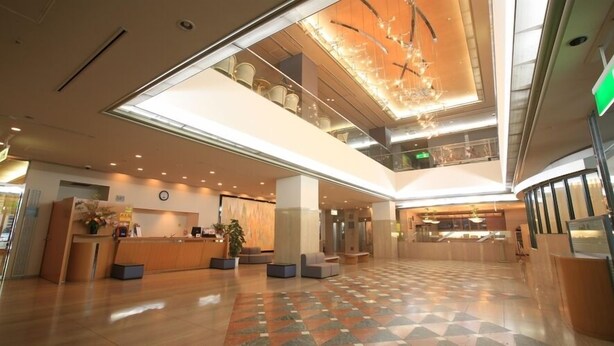Um hall amplo com balcão de check-in, área de estar e teto decorativo.