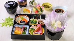 Uma bento japonesa tradicional com diversos alimentos, incluindo peixe, legumes e vegetais em conserva, dispostos cuidadosamente em compartimentos.