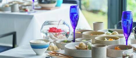Une table dressée avec différents plats et boissons, dont un grand bocal rempli de poissons en guise de centre de table, des bols et des verres.