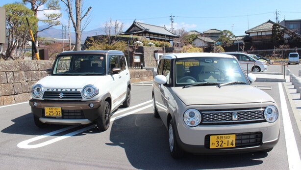 Två bilar står parkerade på en gata med traditionell japansk arkitektur i bakgrunden.