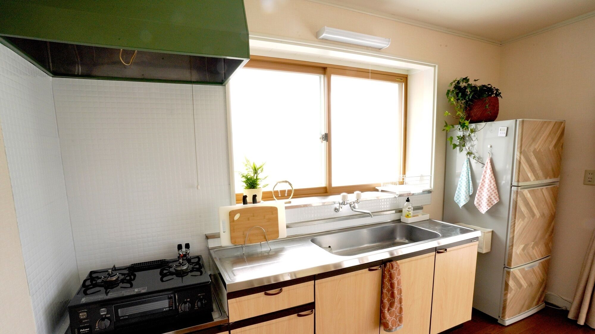 A kitchen with a gas stove, a sink, and a refrigerator.