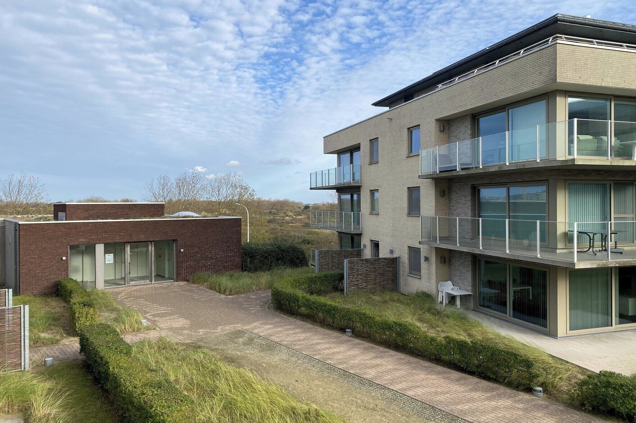 Ein modernes, zweistöckiges Gebäude mit Flachdach, großen Fenstern und einem Balkon.