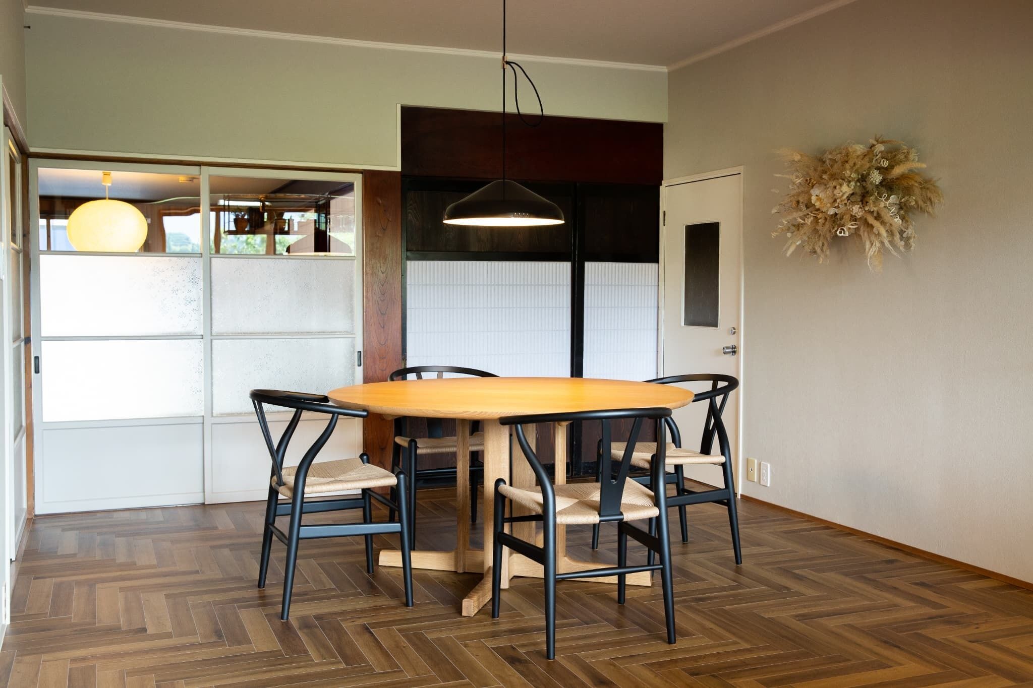 Un comedor con una mesa y sillas de madera, una lámpara colgante y un adorno en la pared.
