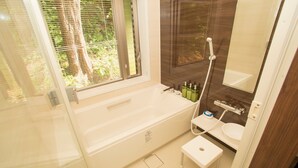 A modern bathroom with a bathtub, a sink, and a window with blinds. - K's Casa Onna Village (Onna)