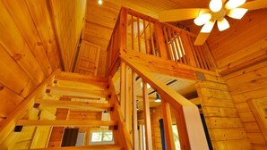 Una escalera de madera con barandilla y un ventilador de techo.