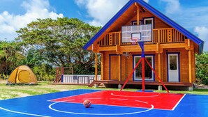 Una cabaña de madera con una cancha de baloncesto al frente.