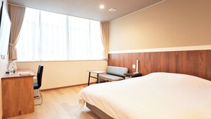 Ein Hotelzimmer mit einem Bett, einem Schreibtisch, einem Stuhl, einem kleinen Tisch und einem Sofa.