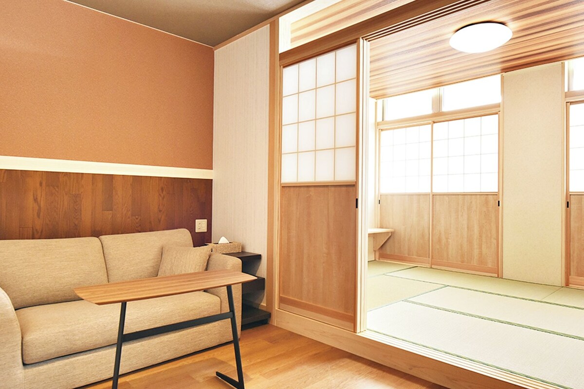 A traditional Japanese room with tatami flooring, a low wooden table, and a sofa.