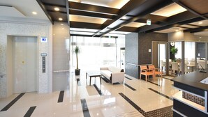 A modern lobby with a reception desk, seating area, and an elevator. - Hotel Nishiyama (Minamisoma)