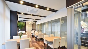 A modern conference room with glass walls, wooden flooring, and white furniture. - Hotel Nishiyama (Minamisoma)