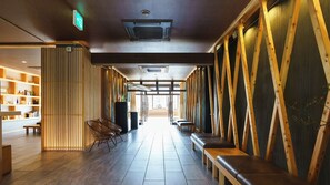 A hallway with wooden paneling, benches, and a bookshelf. - Ryokan Kobushi (Nantan)