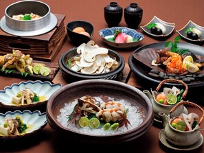 A variety of dishes, including seafood and vegetables, arranged on a table with a traditional Japanese aesthetic. - Ryokan Kobushi (Nantan)