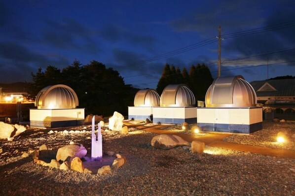 A row of dome-shaped buildings with a central water feature, surrounded by rocks and gravel. - Ryokan Kobushi (Nantan)