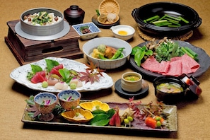 A variety of dishes and food items, including sushi, sashimi, and a hot pot, arranged on a table. - Ryokan Kobushi (Nantan)
