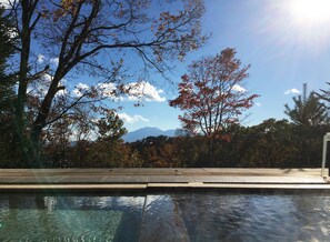 Una piscina amb vistes a arbres i muntanyes al fons.