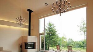 A spacious living room with a fireplace, modern furniture, and large windows offering a view of the outdoors. - Kusatsu Onsen Hotel Kurbio (Kusatsu)