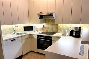 A compact kitchen with a dishwasher, microwave, oven, and a coffee maker. - Beachfront apartment in Nieuwpoort (NIEUWPOORT)
