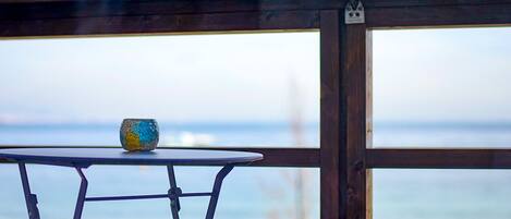 A table with a ceramic mug on it, positioned near a window overlooking a beach.