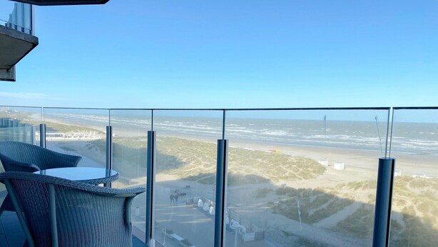 A balcony with a clear view of the beach and distant buildings. - Sea-view apartment on Zeedijk (NIEUWPOORT)