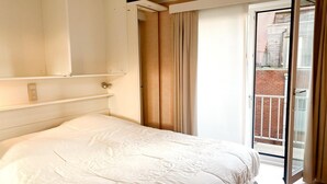 A bedroom with a bed, a sliding door to a balcony, and a light switch on the wall. - Sea-view apartment on Zeedijk (NIEUWPOORT)