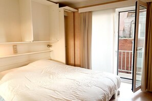 A bedroom with a bed, a sliding door to a balcony, and a light switch on the wall. - Sea-view apartment on Zeedijk (NIEUWPOORT)