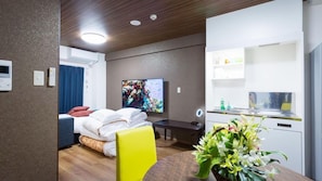 A hotel room with a bed, a desk, a chair, a TV, a kitchenette, and a bathroom. - Kariyushi Condominium Resort Naha Ryujin Hotel Ukishima (Naha)