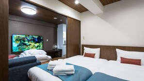 Una habitación de hotel con dos camas, un televisor de pantalla plana, un escritorio y un espejo.