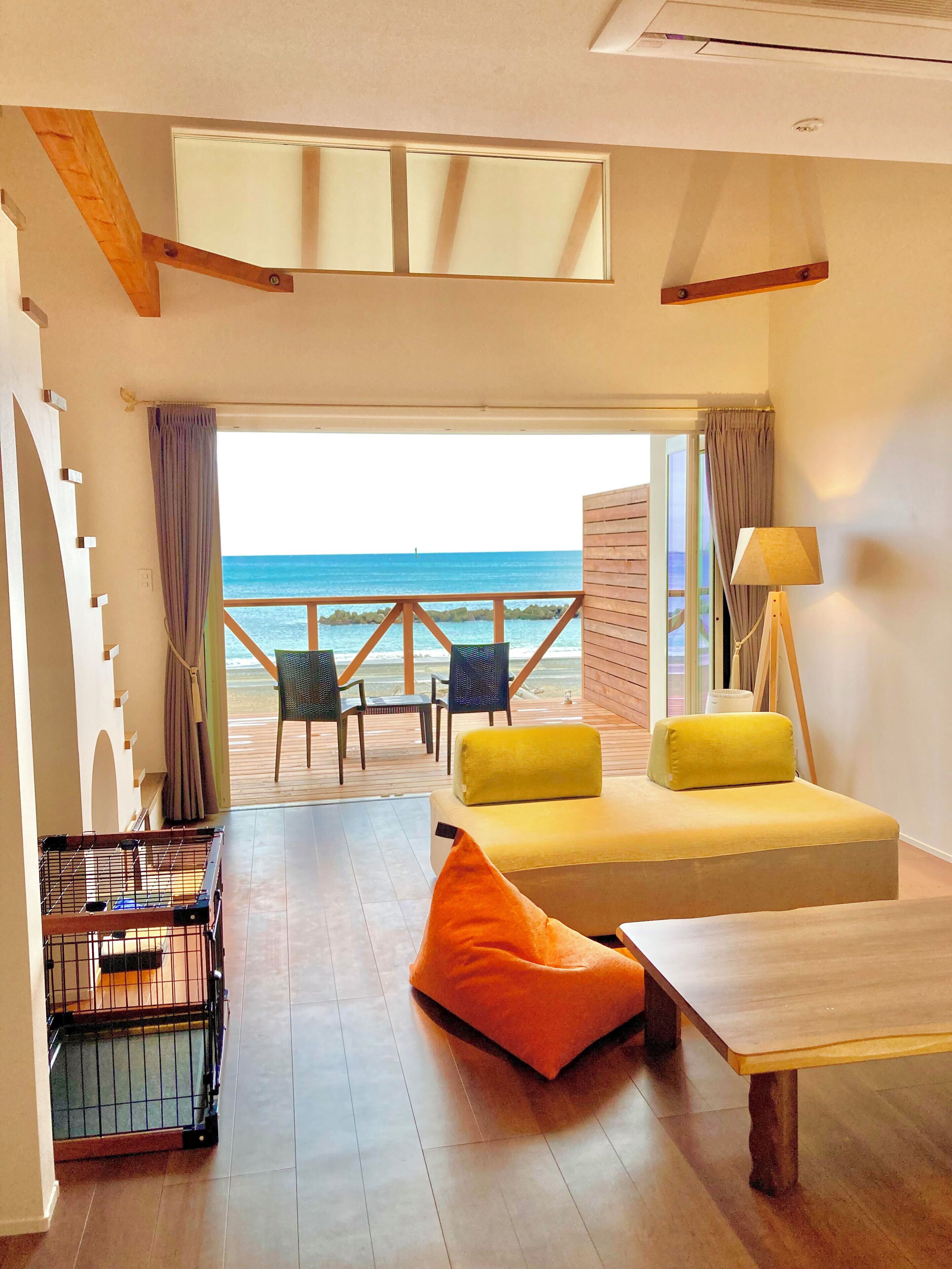 A room with a bed, a table, and a view of the beach.