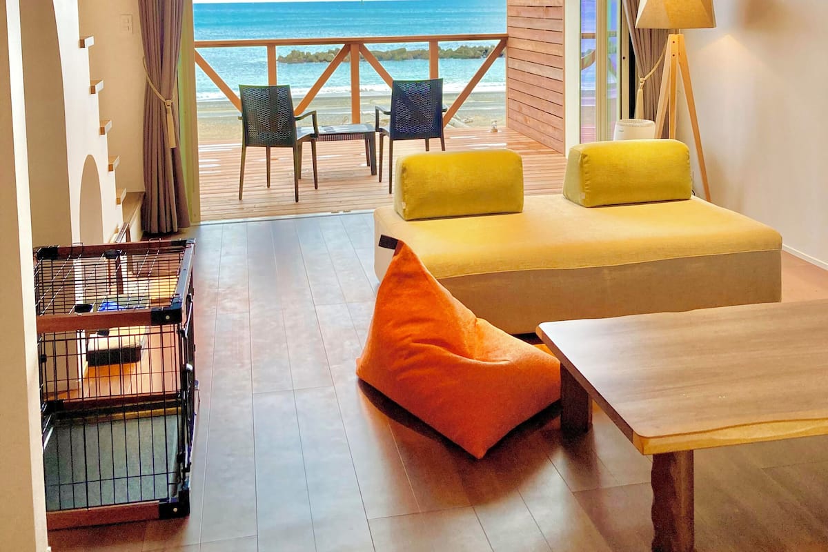 A room with a bed, a table, and a view of the beach.