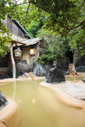 A traditional Japanese building with a wooden exterior, a stone wall, and a small pond with rocks.