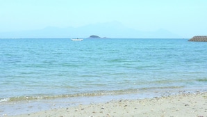 A beach with calm waters, a small boat, and distant mountains. - Yurakutei (Kamiamakusa)