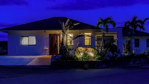 Une maison moderne à deux étages, dotée d’une entrée bien éclairée, d’un élément décoratif aquatique bien visible et d’une enseigne indiquant « Villa Grace ».