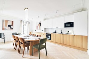 A modern kitchen with white cabinets, a microwave, and a dining area with a round table and chairs. - Splendid Apartment AC- 4BR/8P - Paris 2 (Paris)