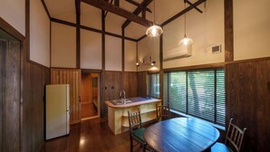 A compact kitchen with wooden walls, a dining table, chairs, and a refrigerator. - Guesthouse Obuse (Obuse)