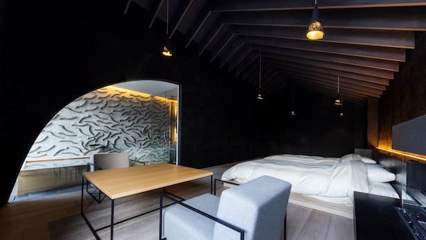 Een moderne slaapkamer met een bed, een houten tafel en een zithoek.